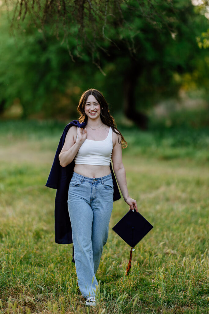 Senior photo with cap and gown in the green grass and trees at Butcher Jones Recreation Site, Salt River, Mesa, Arizona.