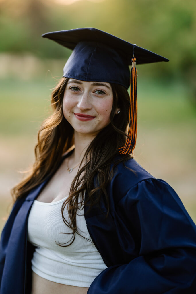 Senior photo headshot with cap and gown in the green grass and trees at Butcher Jones Recreation Site, Salt River, Mesa, Arizona.