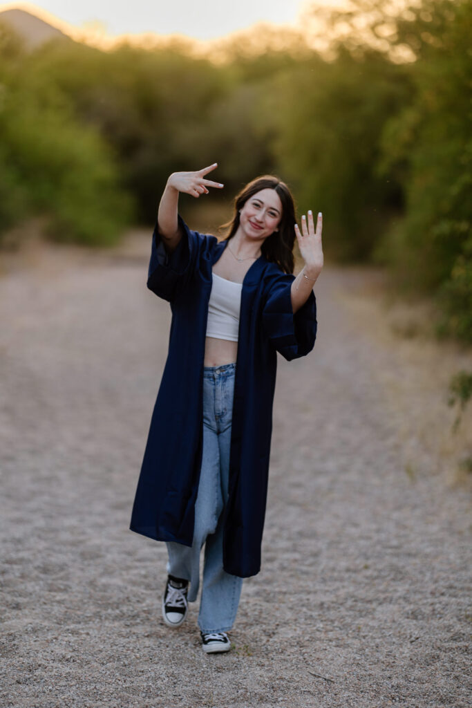 Senior photo with cap and gown in the green grass and trees at Butcher Jones Recreation Site, Salt River, Mesa, Arizona.