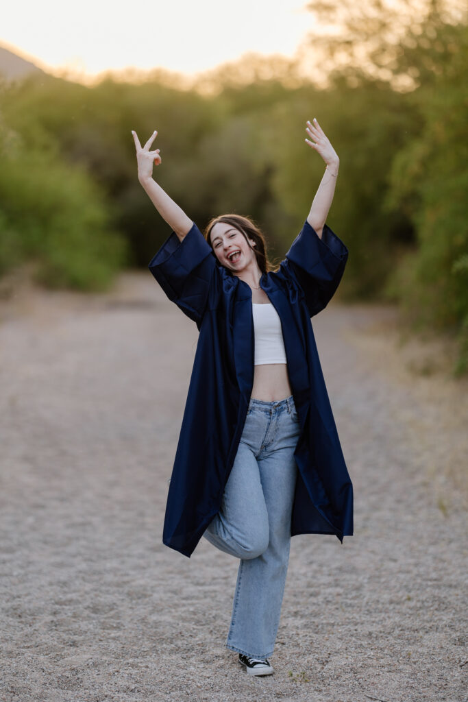 Senior photo with cap and gown in the green grass and trees at Butcher Jones Recreation Site, Salt River, Mesa, Arizona.