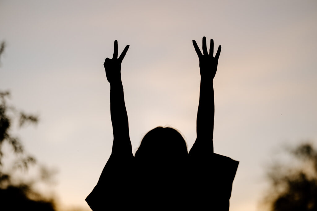 Silhouette of a senior holding up two fingers on one hand and 4 fingers on the other at Butcher Jones Recreation Site, Mesa, Arizona.