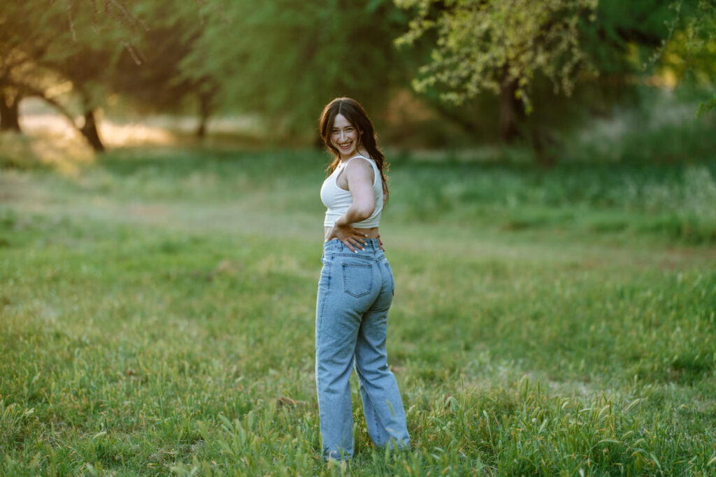 Senior photos in the green grass and trees at Butcher Jones Recreation Site, Salt River, Mesa, Arizona.